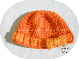 gorro de lana naranja realizado a crochet con cinta y lazo también a crochet