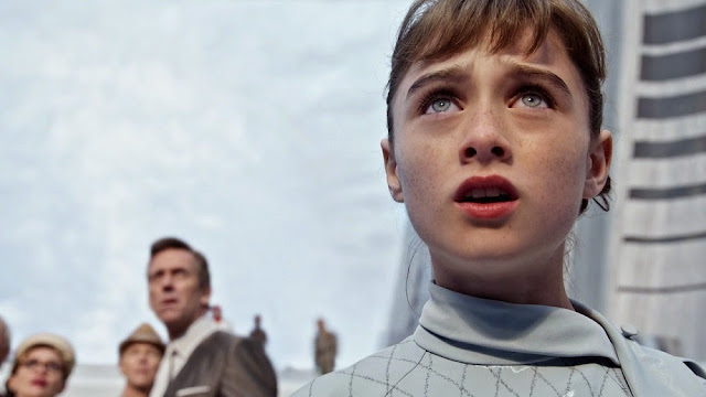The charmingly freckled Raffey Cassidy as Athena the robot. Hugh Laurie as David Nix in the blurred background. Raffey Cassidy Tomorrowland still