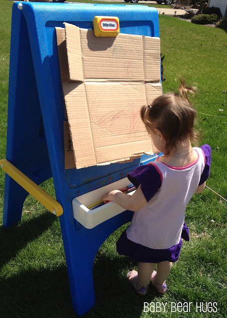 girl drawing outdoors on a fisher price easel