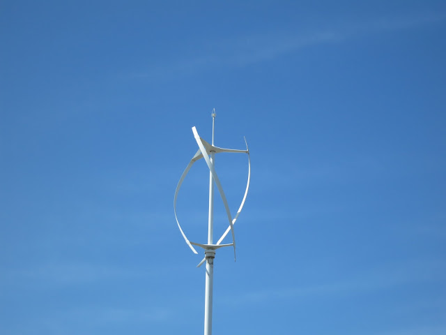 A whirligig type wind turbine - small - white - against blue sky