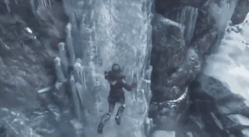 No gif: Tomb Raider pulando para uma montanha de pedra na neve e fincando o martelinho de escalada. 