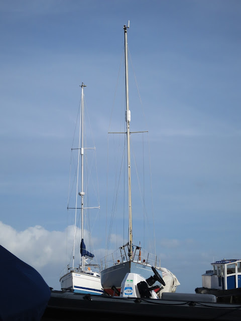 Two boats with tall masts in dry dock.