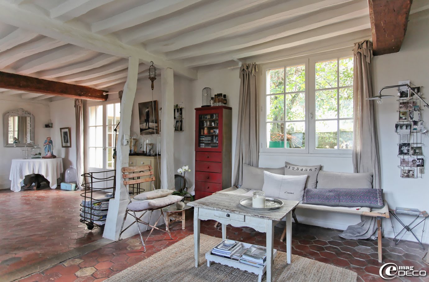 La pièce à vivre de la maison d'hôtes L'Épicerie du Pape avec ses colombages évidés et repeints en blanc et son sol recouvert d’anciennes tomettes en terre cuite