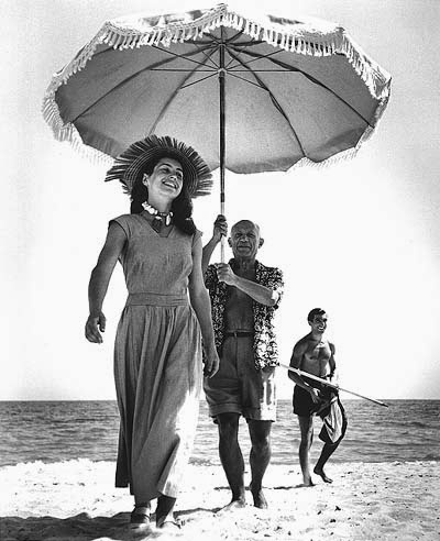 Robert Capa: Picasso and his muse Francoise Gilot Picasso hold a parasol over his muse Francoise Gilot on the sandy beach