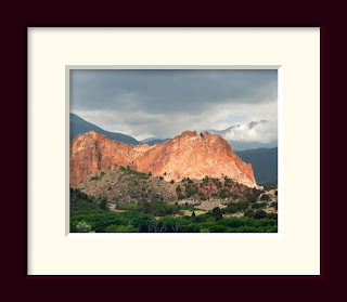 An iconic red stone mountain rises up against a stormy sky in Colorado's Garden of the Gods.