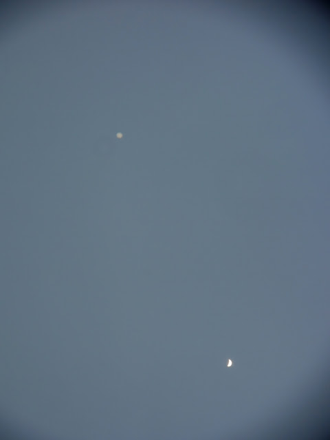 Zoomé, via un petit télescope (x60), Vénus en croissant, comme une petite Lune..., et, au-dessus, Jupiter qui montre ses nuages équatoriaux... Leur taille en apparence est presque semblable