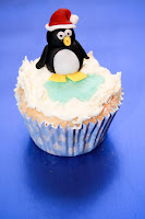 winter wonderland cupcakes, winter theme, Christmas, snow scene, snow, snowflakes, cold, icy, buttercream, cake, seasonal, penguin, penguin cake topper, Father Christmas hat, penguin character Winter theme cupcake topped with buttercream snow and a fondant penguin cake topper
