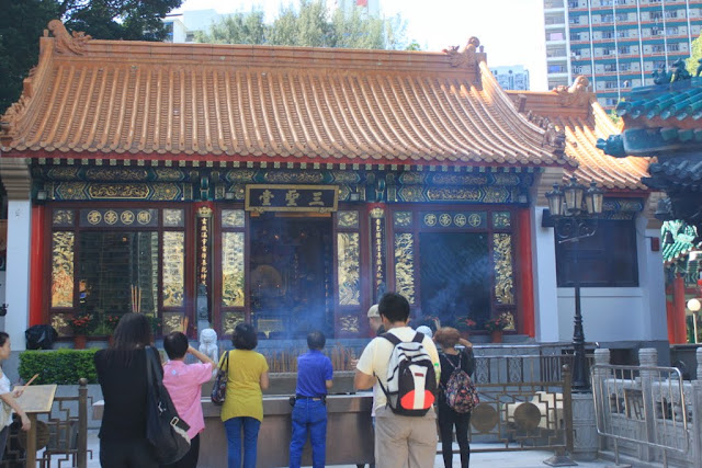 Visitors praying in front of the God with burning intense sticks at Wong Tai Sin Temple in Kowloon, Hong Kong Visitors praying in front of the God with burning intense sticks at Wong Tai Sin Temple in Kowloon, Hong Kong
