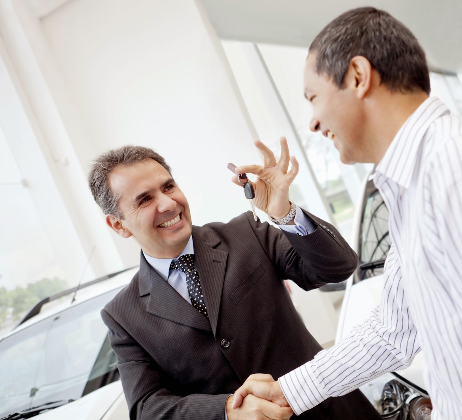 happy owner of new car shaking hands with salesperson