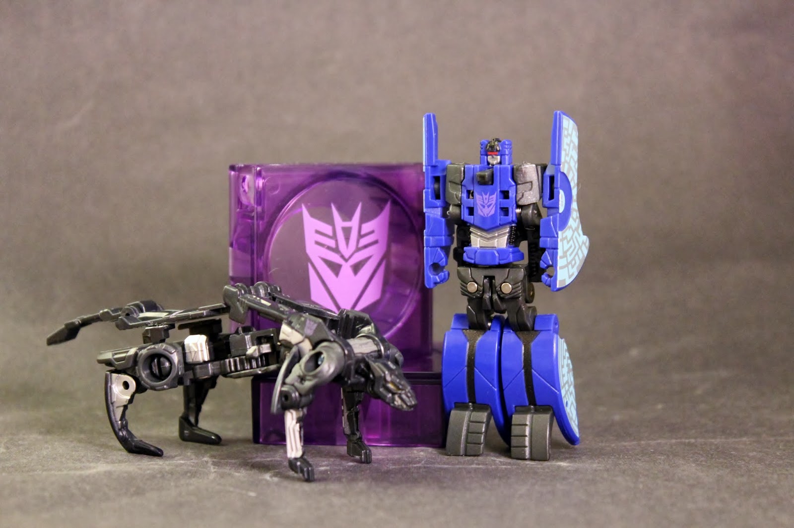 Ravage and Rumble, Robot Mode Ravage and Decepticon Rumble on display next to containers.