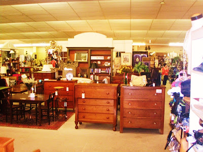 antiqes at an antique mall, lots of wood chest and tables and lamps and pictures and plates