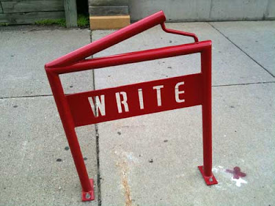 Red metal bike rack shaped like an open book with the word WRITE in open stencil letters
