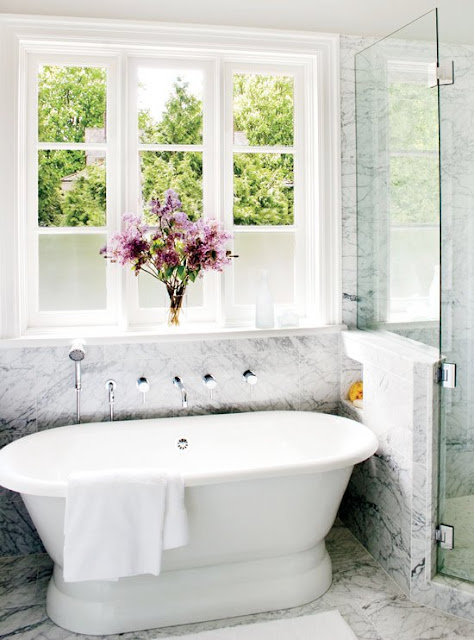 bathroom with stand in tub, marble floors and a large encasement window