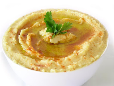 Hummus (puré) Recipiente con hummus decorado con pimentón molido y hoja de perejil