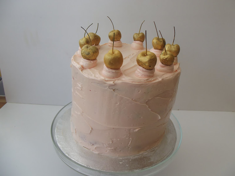 Here is this lovely covered rainbow cake wih a cherry and almond butter cream.