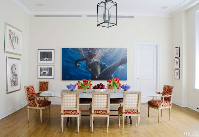 apartment dining room with upholstered gingham and vichy louis xvi chairs, wood floors, a large pendant light with lots of art on the walls