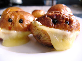 Two roasted potatoes, cut in half with melted cheese in the middle and peppercorns inserted to look like eyes.