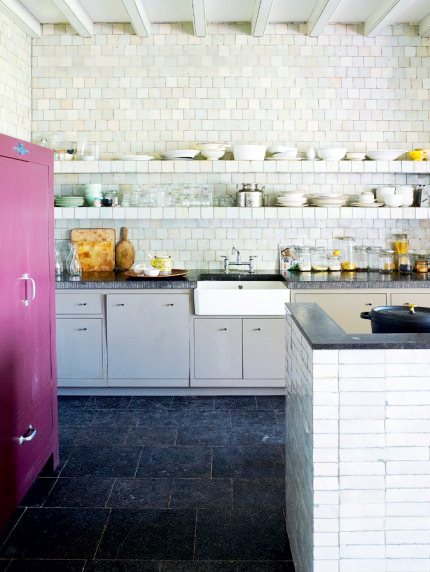 Zellige tiles used as a backsplash in a French kitchen with dark marble counters, floating sheleves and white cabinets