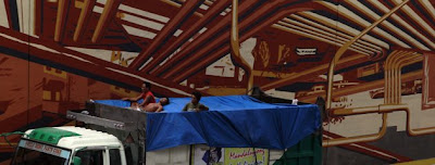 Filipino workers rest on top of a truck passing along a wall mural painted with air-purifying paint in EDSA, a main highway in Metro Manila February 1, 2012.