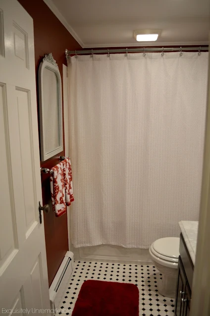 White waffle shower curtain hanging in a red bathroom, with a black and white tile floor