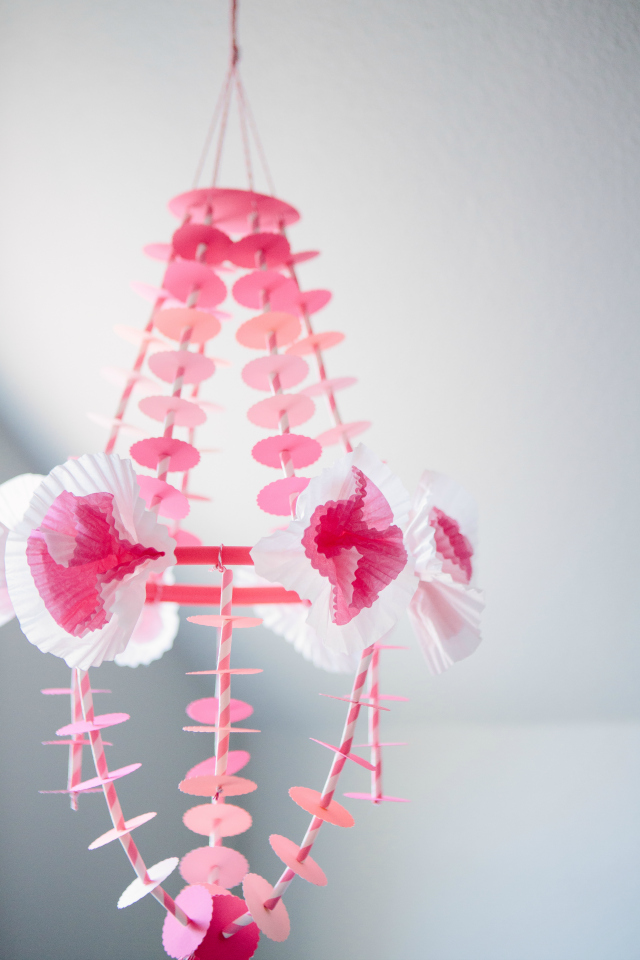 This delicate paper chandelier comes together easily with a paper punch, striped straws, and cupcake wrapper flowers! || http://designimprovised.com