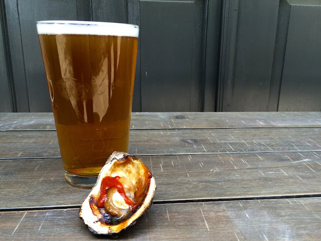 A pint of Tin Roof Brewing's Turnrow Harvest Ale and the Asian Style Chargrilled Oyster at Jolie Pearl Oyster Bar