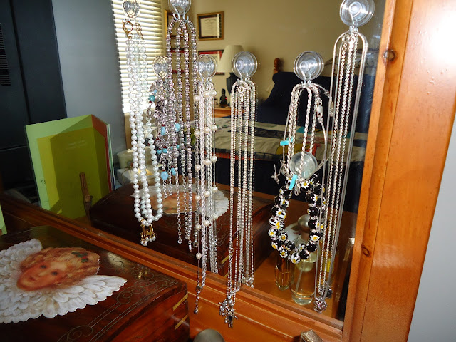 necklaces hung from suction cups stuck to a mirror in a bedroom