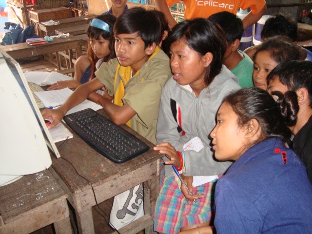 Students crowd around a single computer