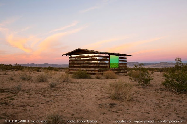 Cabaña transparente de madera y espejos en un paisaje desértico