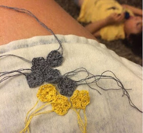 Miniature granny squares in yellow and white resting on a knee.