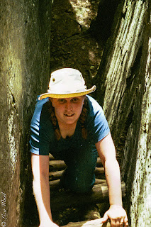 Woman climbing ladder in rock crevice