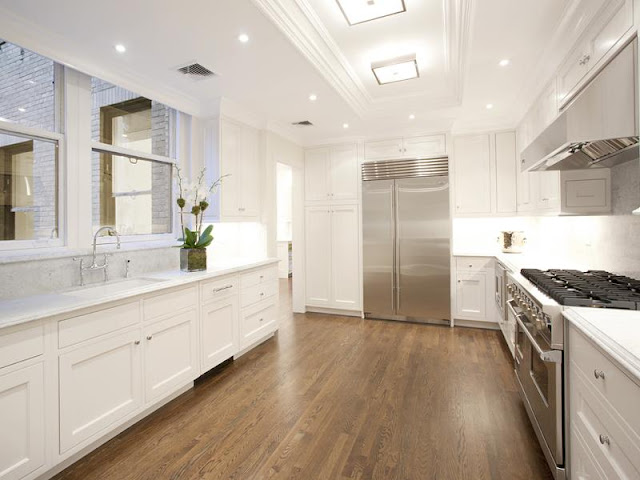 kitchen with Carara marble counters, stainless steel appliances, wood floors and recessed panel white cabinets