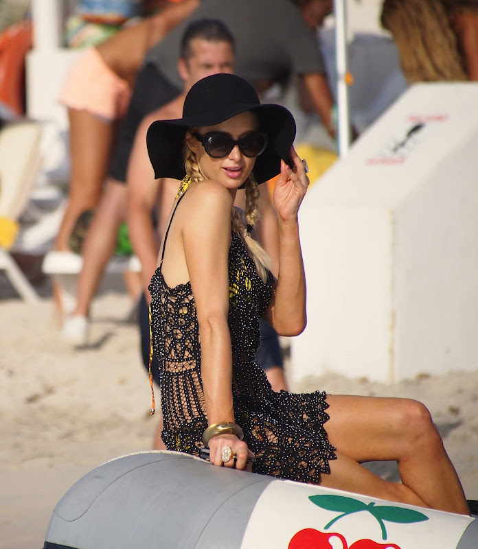 Paris Hilton sitting in a boat wearing a black hat and sunglasses