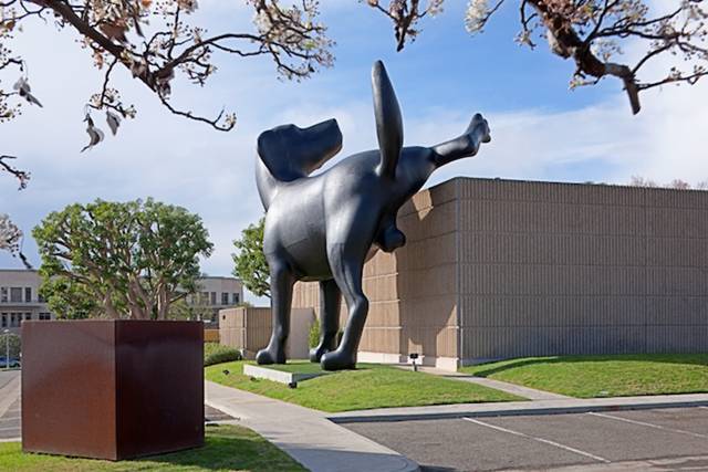 A 28-foot-tall sculpture of a black Labrador relieving itself is currently installed on the side of the Orange County Museum of Art (OCMA) in Newport Beach, California. The installation, known simply as Bad Dog, is a new outdoor piece by artist Richard Jackson that is claiming its temporary territory throughout the run of the 74-year-old artist's first retrospective exhibit titled Richard Jackson: Ain't Painting a Pain.