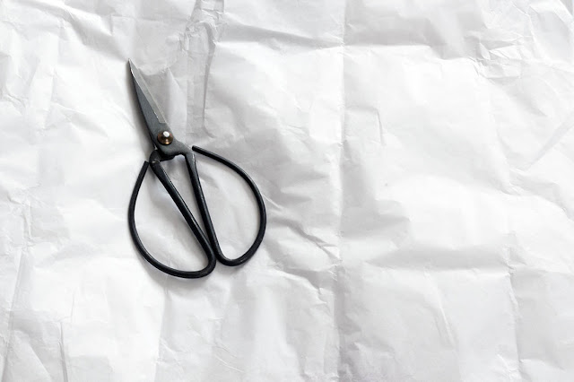 high key: black pair of scissors on white paper