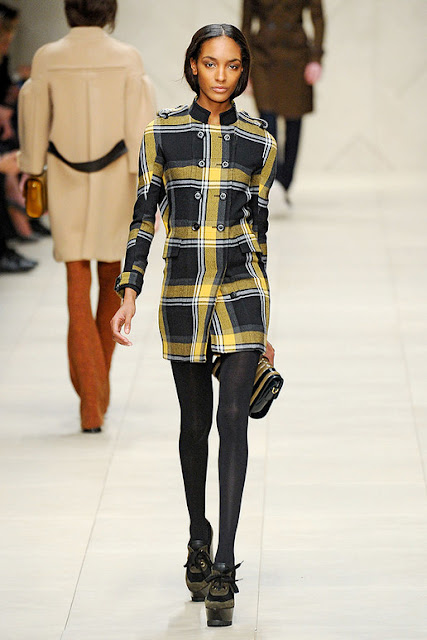 Model from Burberry Prorsum's Fall 2011 RTW is wearing a black and yellow plaid dress with black tights and ankle boots