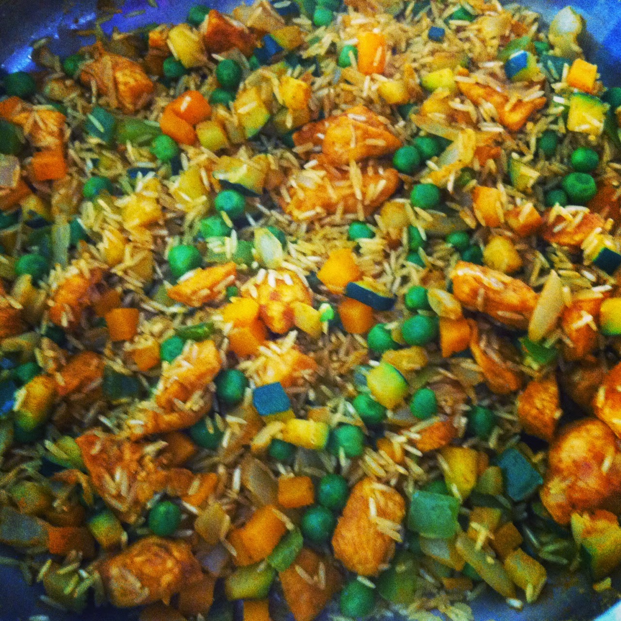 Arroz con pollo y verduras al curry, añadiendo el arroz y el curry.