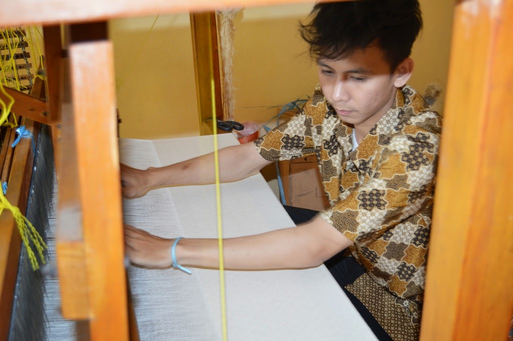Using loom to weave songket