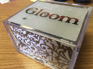 Closed box with colored "Gloom" logo sticker on top and black and white scrollwork scrapbook paper lining the inside sides of box