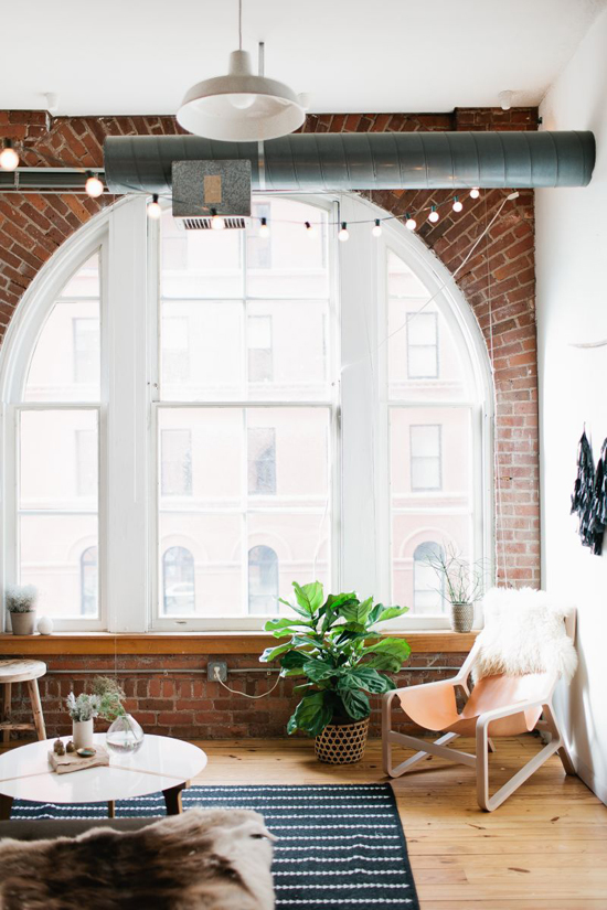 Exposed brick walls and large windows in the house of Madelynn Furlong. Photo by Wing Ta via The Everygirl.