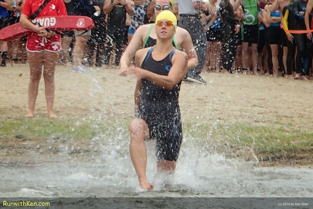 Up-close action photo of triathletes LEAPING into the open water at the Triathlon at Lake Pearl in Wrentham, MA. Sports Photography from Inside the Pack by Ken Skier, the Swimming Photographer. (RunwithKen.com) The Triathlon at Lake Pearl is produced by the Hockomock Area YMCA. (hockymca.org)