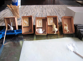 Five box brooches drying on a on a drying jig, with camps, toothpicks and glue.