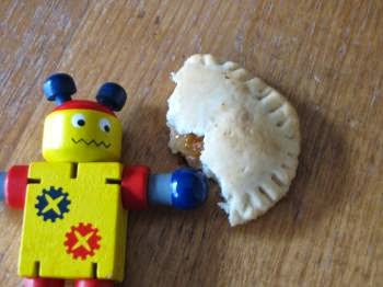 Un piccolo robot giocattolo accanto a un biscotto