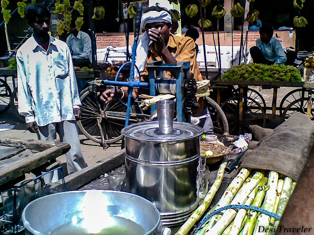 making sugarcane juice from a hand operated machine on a street of India