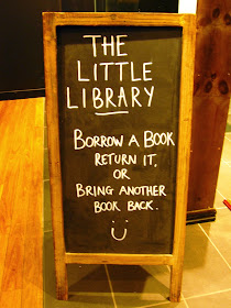 The Little Library in Melbourne Central: blackboard instruction sign saying 'Borrow a book return it. Or bring another book back.'