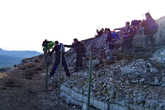 Excursionistas saltan una valla para incorporarse al GR7 cerca de la cumbre del Tejo, entre Chera y Requena. blog "m&aacute;s de mil"