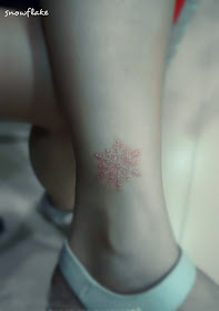 White ink snowflake tattoo on the ankle