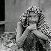 Smiling of rural woman in front of fire in summer morning.