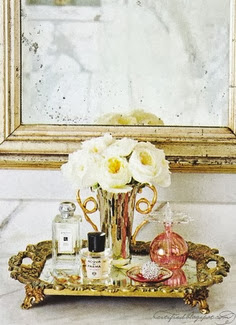 perfume bottles and white roses on a dressing table