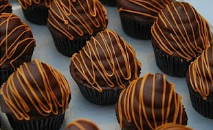 close up of chocolate dipped cupcakes with light chocolate drizzle on top